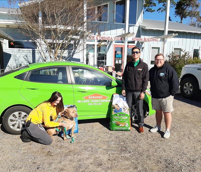 Humane Society reps and SERVPRO personnel with puppy Flash in front of SERVPRO car